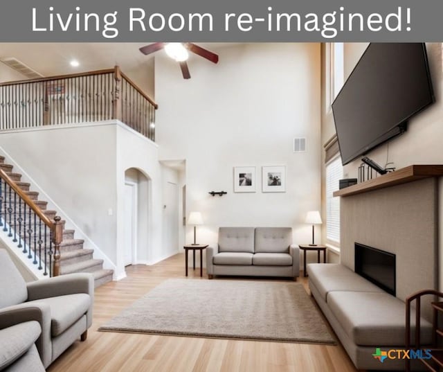 living room with ceiling fan, light hardwood / wood-style flooring, and a towering ceiling