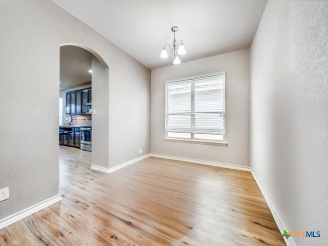 spare room with light wood-type flooring and an inviting chandelier