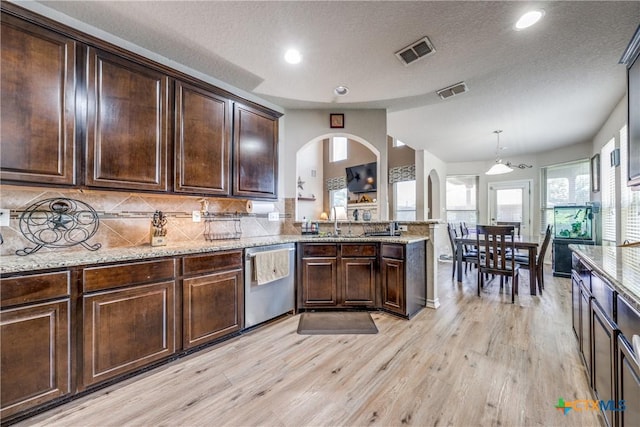 kitchen featuring pendant lighting, dark brown cabinetry, tasteful backsplash, stainless steel dishwasher, and light hardwood / wood-style flooring