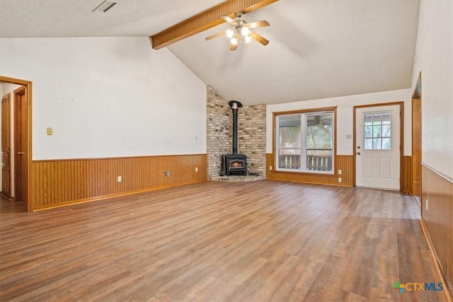 3927 Amanda Dr, Salado, TX 76571 - unfurnished living room featuring wainscoting, wood finished floors, a wood stove, a ceiling fan, and a textured ceiling