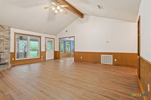 3927 Amanda Dr, Salado, TX 76571 - unfurnished living room with beamed ceiling, wainscoting, wood finished floors, a ceiling fan, and a textured ceiling