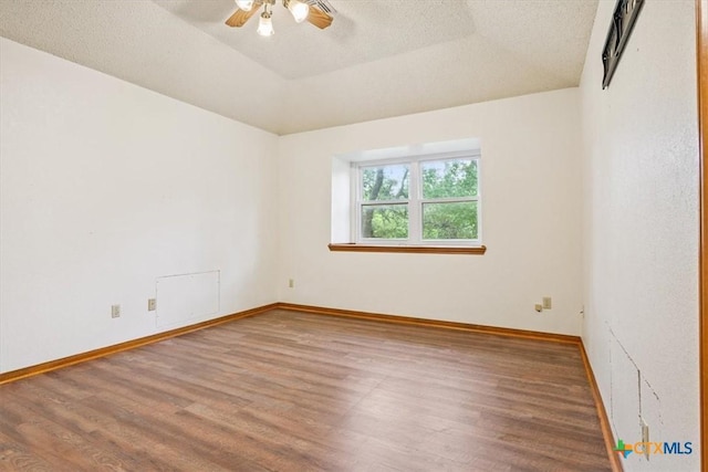 3927 Amanda Dr, Salado, TX 76571 - empty room featuring wood finished floors, a ceiling fan, a raised ceiling, and a textured ceiling