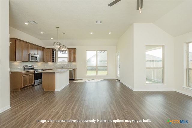 kitchen featuring stainless steel appliances, hanging light fixtures, lofted ceiling, a center island, and dark wood-type flooring