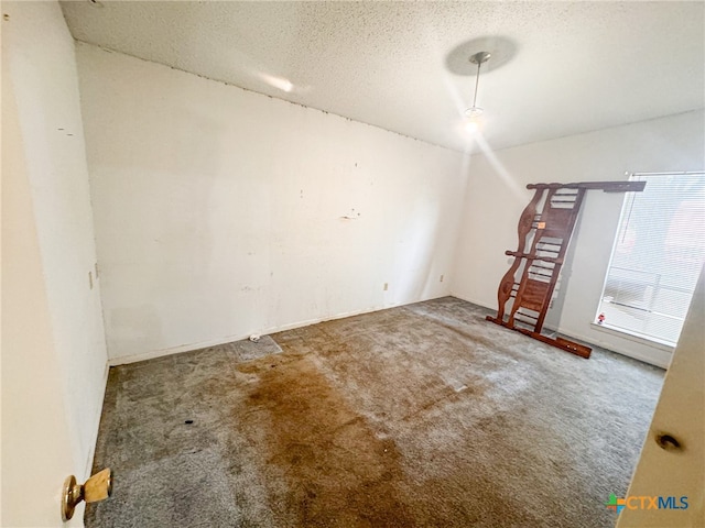 carpeted empty room with a textured ceiling