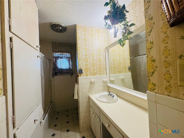 bathroom featuring tile walls, vanity, a textured ceiling, and tile patterned floors