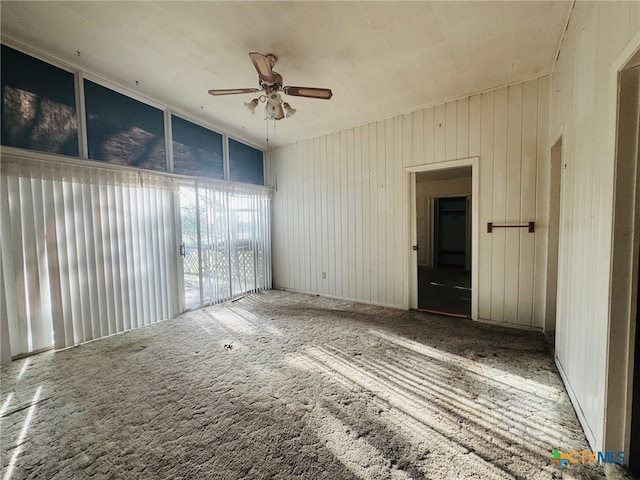 spare room with wood walls and ceiling fan