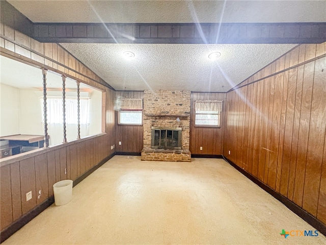 unfurnished living room with wood walls, a healthy amount of sunlight, and a textured ceiling