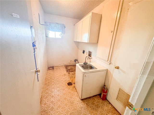 laundry room with a textured ceiling, washer hookup, cabinets, and sink