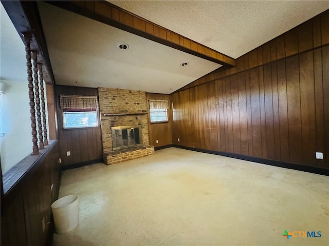 unfurnished living room featuring a fireplace, wood walls, a textured ceiling, and vaulted ceiling