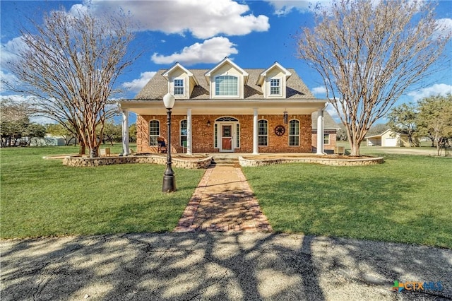 new england style home with a porch, brick siding, and a front lawn