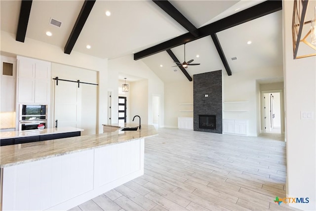 1193 Country Pike, Canyon Lake, TX 78133 - kitchen featuring a barn door, beamed ceiling, stainless steel oven, a ceiling fan, and high vaulted ceiling