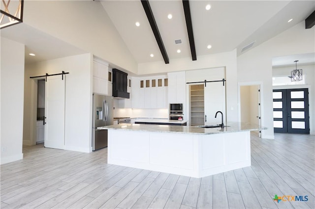 1193 Country Pike, Canyon Lake, TX 78133 - kitchen featuring a barn door, appliances with stainless steel finishes, light wood-style floors, a large island, and beam ceiling