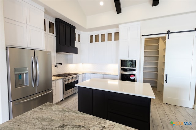 kitchen with stainless steel appliances, a barn door, light hardwood / wood-style flooring, lofted ceiling with beams, and white cabinets