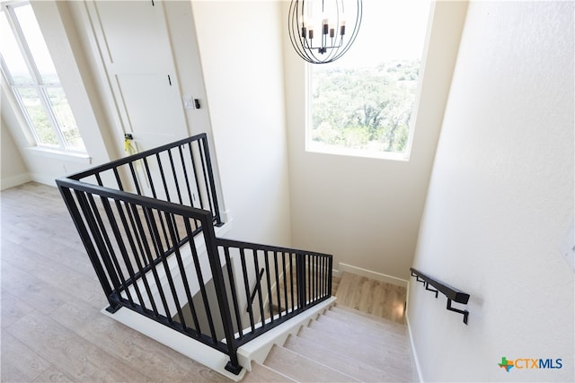 stairway with hardwood / wood-style floors and a chandelier