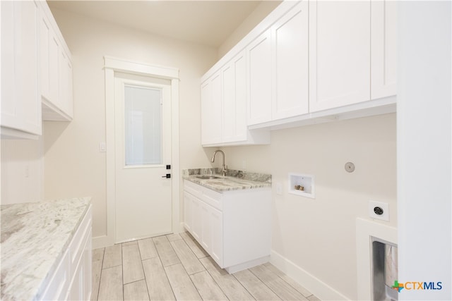 clothes washing area with sink, cabinets, electric dryer hookup, light hardwood / wood-style flooring, and hookup for a washing machine