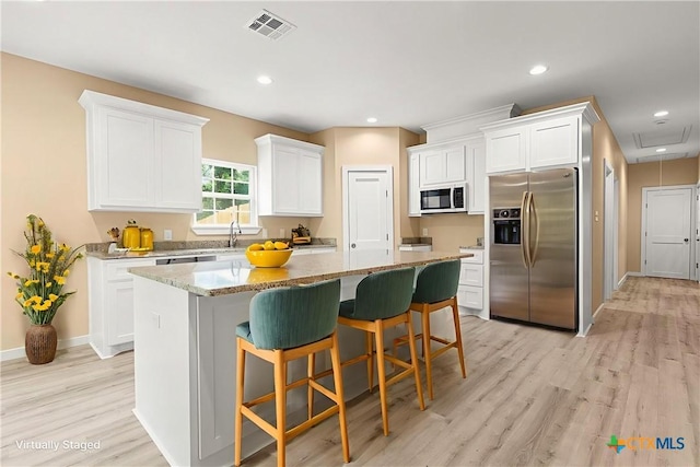 1700 Proctor Ave, Waco, TX 76708 - kitchen with stainless steel refrigerator with ice dispenser, a center island, a kitchen bar, white cabinets, and light wood-style flooring