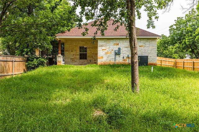 1700 Proctor Ave, Waco, TX 76708 - back of property with stone siding, a fenced backyard, and roof with shingles