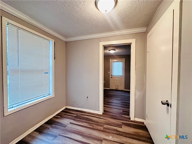 empty room featuring dark hardwood / wood-style flooring, a textured ceiling, and ornamental molding