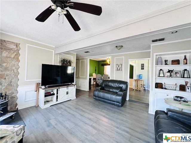 living room with hardwood / wood-style floors, a textured ceiling, and crown molding