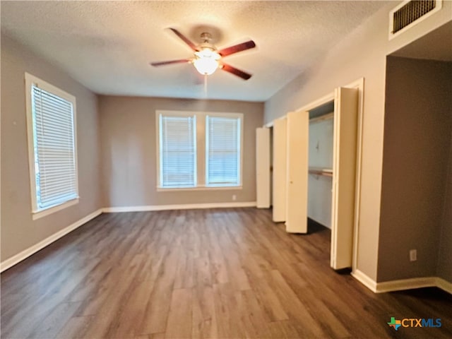 unfurnished bedroom with multiple windows, hardwood / wood-style floors, ceiling fan, and a textured ceiling