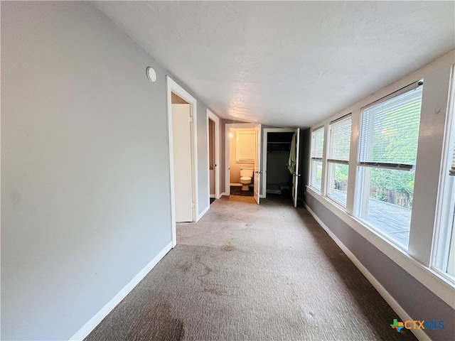 unfurnished room featuring a textured ceiling, vaulted ceiling, and carpet