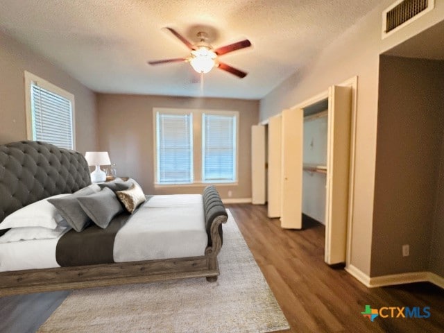 bedroom featuring multiple windows, wood-type flooring, ceiling fan, and a textured ceiling