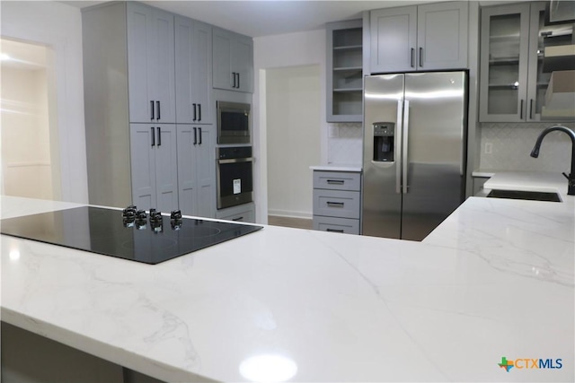 2704 Loma Vista Ave, Victoria, TX 77901 - kitchen with appliances with stainless steel finishes, gray cabinetry, glass insert cabinets, and decorative backsplash