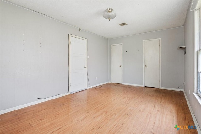 spare room with light wood-style floors, baseboards, and visible vents