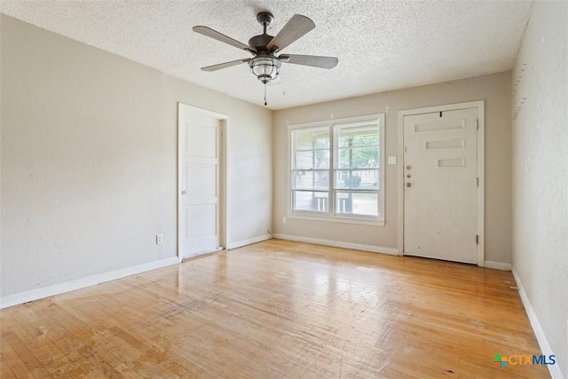 empty room featuring baseboards, a textured ceiling, ceiling fan, and light wood-type flooring