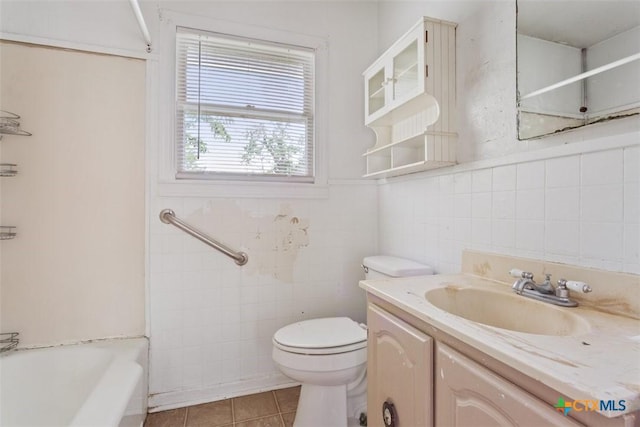 full bathroom with tile walls, tile patterned floors, a wainscoted wall, vanity, and toilet