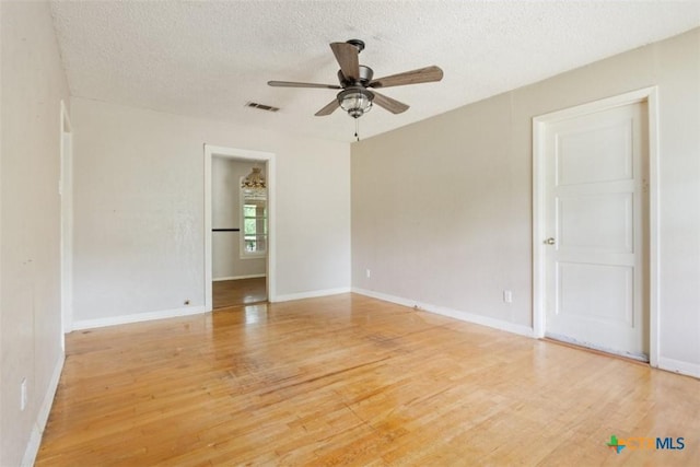 empty room with a ceiling fan, a textured ceiling, visible vents, baseboards, and light wood-style flooring