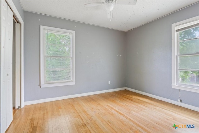spare room with plenty of natural light, baseboards, ceiling fan, and hardwood / wood-style floors