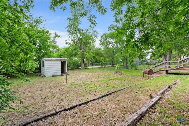 view of yard featuring a shed, an outbuilding, and fence