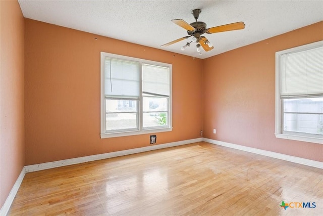 spare room with ceiling fan, baseboards, plenty of natural light, and wood finished floors