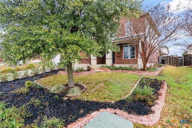 view of property hidden behind natural elements featuring fence, a front lawn, and brick siding