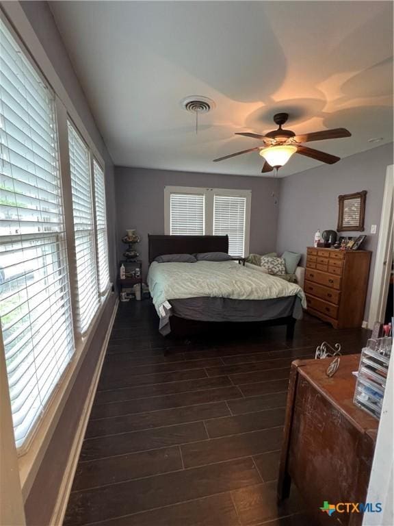 bedroom with baseboards, visible vents, a ceiling fan, and dark wood-type flooring