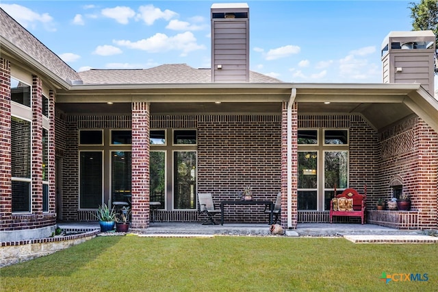 959 Wilderness Trl, New Braunfels, TX 78132 - rear view of house with a chimney, brick siding, a patio area, and a lawn