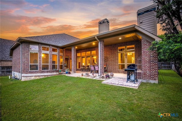 959 Wilderness Trl, New Braunfels, TX 78132 - back of house at dusk with a chimney, brick siding, a patio, and roof with shingles