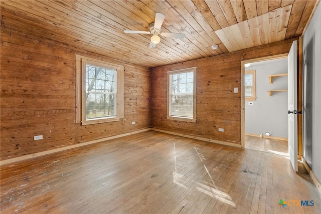 interior space featuring wooden walls, wooden ceiling, hardwood / wood-style floors, ceiling fan, and a healthy amount of sunlight