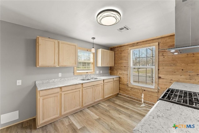 kitchen featuring range hood, wood walls, plenty of natural light, and hanging light fixtures