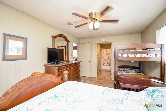 bedroom with crown molding, light hardwood / wood-style floors, ceiling fan, and ensuite bath