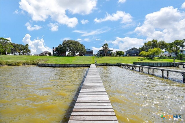 view of dock with a yard and a water view