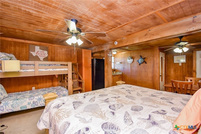 bedroom with ceiling fan, wooden walls, black fridge, and wood ceiling