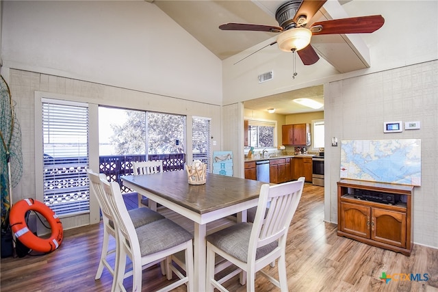 dining room featuring high vaulted ceiling, plenty of natural light, ceiling fan, and light hardwood / wood-style flooring