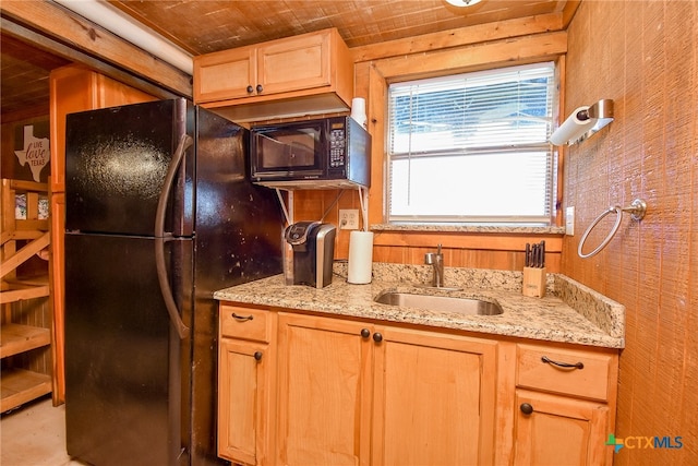 kitchen featuring wood ceiling, black appliances, wooden walls, sink, and light stone countertops