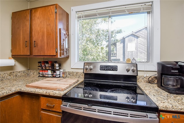 kitchen featuring stainless steel electric stove and light stone counters