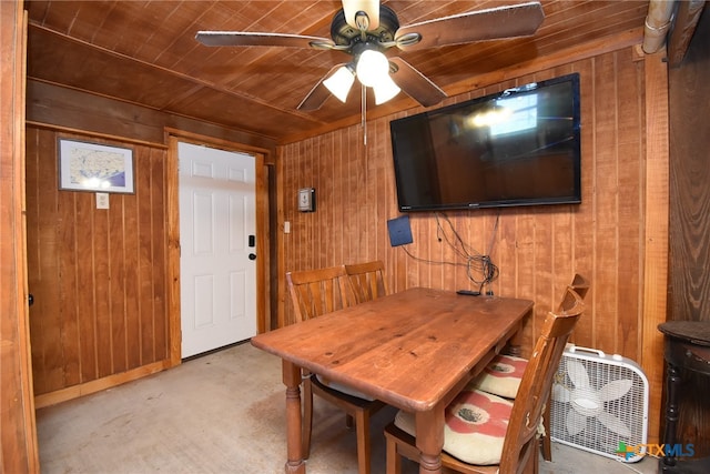 dining area featuring wooden ceiling, ceiling fan, and wooden walls