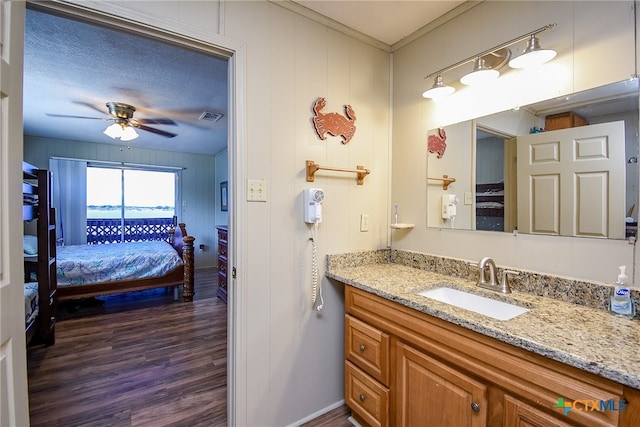 bathroom featuring a textured ceiling, hardwood / wood-style flooring, ornamental molding, vanity, and ceiling fan