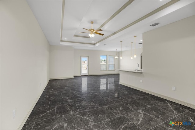 empty room with a raised ceiling, ceiling fan, and sink