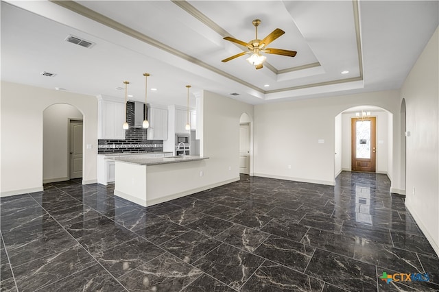 kitchen featuring a raised ceiling, decorative light fixtures, white cabinetry, and light stone counters